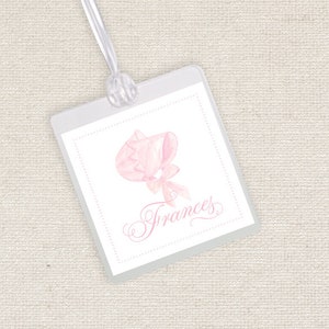 May include: A white tag with a pink watercolor illustration of a bonnet and the word "Frances" in cursive.