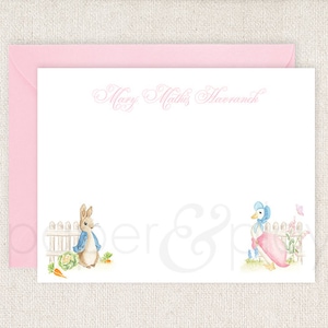 May include: A pink stationery set with a white envelope and a white card with a pink border. The card has a handwritten name "Mary Mathis Moran" at the top and illustrations of Peter Rabbit and Jemima Puddle-Duck at the bottom.