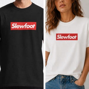 May include: Black and white crew neck t-shirts. Each shirt features the word "Slewfoot" in white text inside a red rectangular box. The shirts are a casual style.