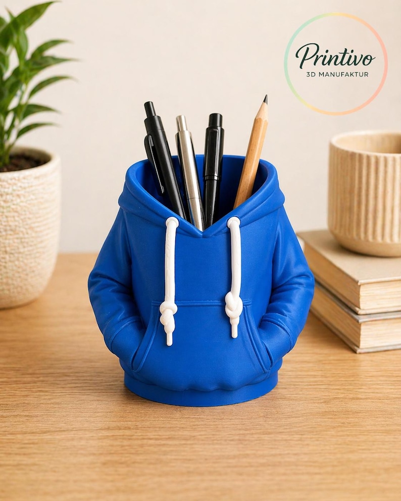 May include: A royal blue desk organizer shaped like a hoodie, with white drawstrings and a front pocket. The organizer holds pens and a pencil. The Printivo logo is visible in the background.