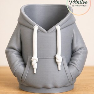 May include: A gray 3D-printed hoodie-shaped container with white drawstrings and a front pocket. The container has a hood and is designed to resemble a miniature sweatshirt. The Printivo logo is visible in the upper right corner.