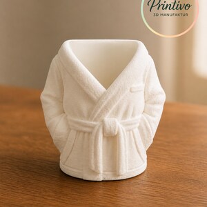 May include: A white 3D-printed decorative planter shaped like a bathrobe. The planter has a textured surface, a belted waist, and sleeves. The Printivo logo is visible in the upper right corner.