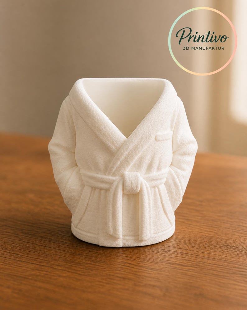 May include: A white 3D-printed decorative planter shaped like a bathrobe. The planter has a textured surface, a belted waist, and sleeves. The Printivo logo is visible in the upper right corner.
