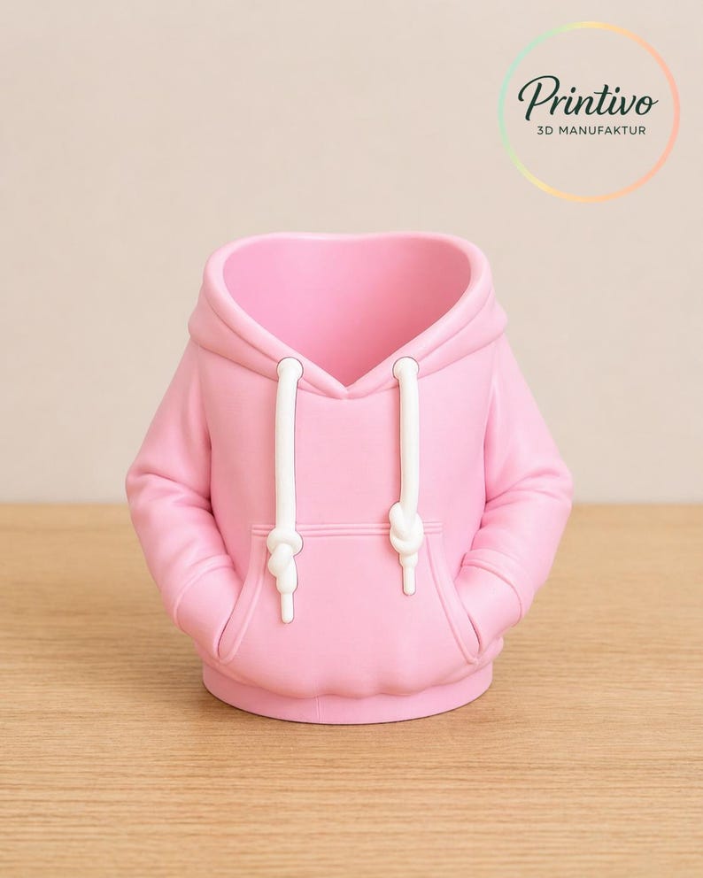 May include: A pink hoodie-shaped container with white drawstrings and pockets. The container is made of a smooth material and sits on a wooden surface. The Printivo logo is visible in the background.