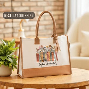 May include: A white ceramic mug with a black handle and the text "But First, Coffee" in a bold, black font. The mug is set against a blurred background, suggesting a cozy setting.