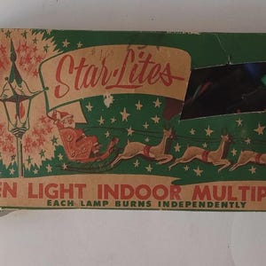 Könnte beinhalten: Vintage Weihnachtsbeleuchtungs-Set-Box mit grünem und braunem Design. Die Box zeigt den Text "Star Lites" und einen Weihnachtsmann in einem Schlitten, der von Rentieren gezogen wird. Auf der Box steht "Seven Light Indoor Multiple Set".