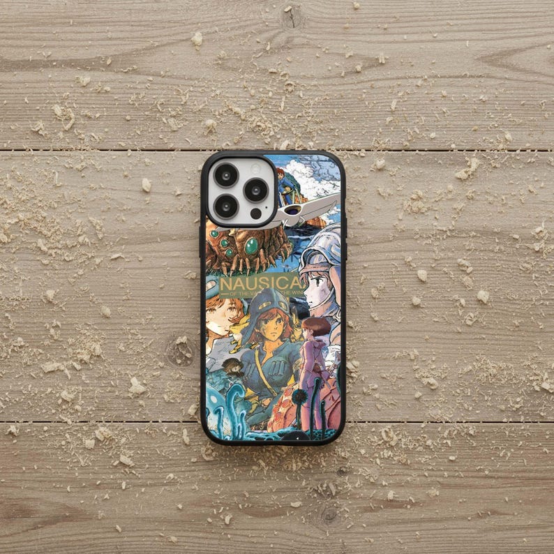 May include: Black phone case featuring a colorful anime-style illustration with the word "NAUSICA" in white. The design includes characters and imagery from the anime series, set against a blue and green background.