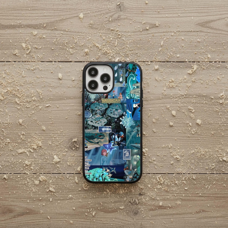 May include: A black iPhone case featuring a collage of blue and teal images with the word "NAUSICAA" visible. The case has a glossy finish and a black border, set against a light brown wooden surface.