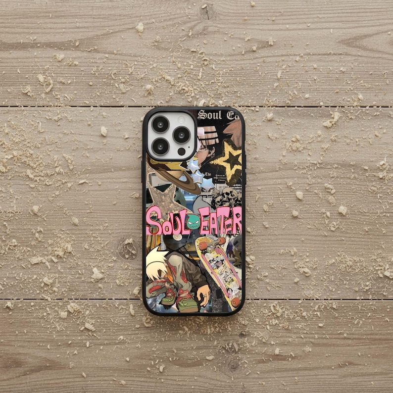 May include: Black phone case with a colorful collage design featuring the text "Soul Eater". The design includes a skateboard, stars, and anime-style illustrations. The case is on a light brown, wood-grain surface.