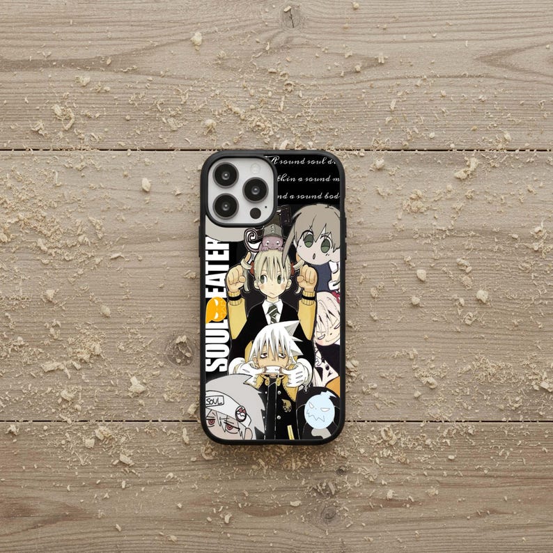 May include: Black phone case featuring anime characters from Soul Eater. The case has a black border and a colorful design with multiple characters. The text "SOUL EATER" is printed vertically on the left side of the case.