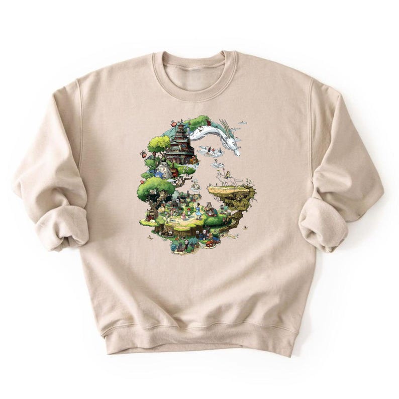 May include: Beige sweatshirt featuring a colorful illustration of a fantasy landscape with a dragon, buildings, and figures. The design is printed on the front of the long-sleeved, crew neck sweatshirt.