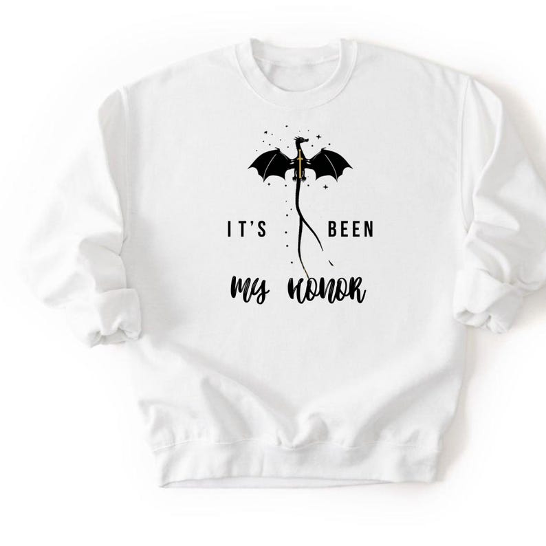 Puede incluir: Sudadera blanca con un dise&ntilde;o de drag&oacute;n negro y el texto "IT'S BEEN MY HONOR". El drag&oacute;n tiene las alas extendidas y est&aacute; posicionado encima del texto. La sudadera tiene mangas largas y cuello redondo.