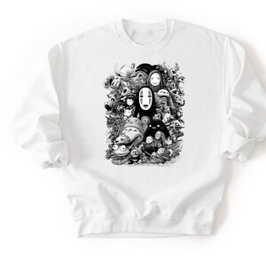 May include: White crewneck sweatshirt featuring a black and white graphic of various animated characters. The design includes faces and figures from a popular animated film. The sweatshirt has long sleeves and a classic fit.