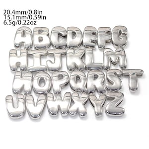May include: A set of silver-colored metal alphabet letter charms arranged in rows from A to Z. Each letter has a smooth, rounded, bubble-like appearance. Text on the image indicates dimensions of 20.4mm/0.8in by 15.1mm/0.59in and a weight of 6.5g/0.22oz.