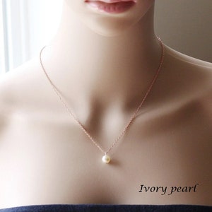 May include: A delicate rose gold chain necklace with a single ivory pearl pendant. The necklace is on a mannequin's neck. The text "Ivory pearl" is below the necklace.