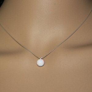 May include: A silver chain necklace with a white opal pendant.