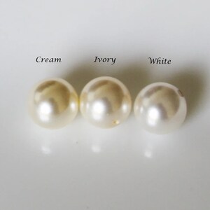 May include: Three round pearls in different shades of white: cream, ivory, and white.