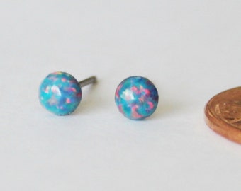 May include: A pair of small, blue and pink opal stud earrings. The earrings are about the size of a ten pence piece.