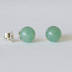 May include: A pair of silver stud earrings with round green gemstone accents.