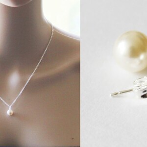 May include: A simple silver necklace with a single pearl pendant and a pair of pearl stud earrings. The pearls are white and round.