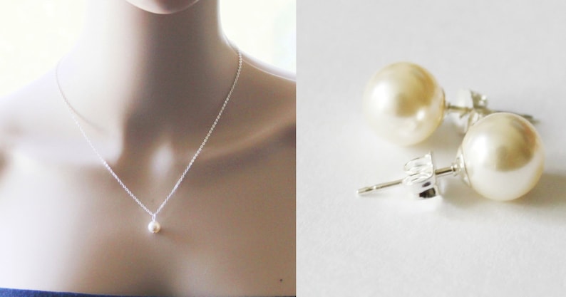 May include: A simple silver necklace with a single pearl pendant and a pair of pearl stud earrings. The pearls are white and round.