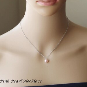 May include: A delicate silver chain necklace with a single pink pearl pendant.  Pink Pearl Necklace.