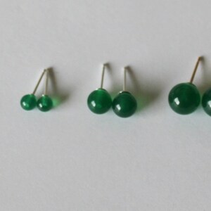 May include: Three pairs of green gemstone earrings with silver posts. The earrings are different sizes, with the largest pair being about the size of a dime.