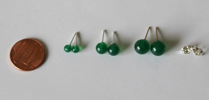 May include: Three pairs of green gemstone earrings with silver posts. The earrings are different sizes, with the largest pair being about the size of a dime.
