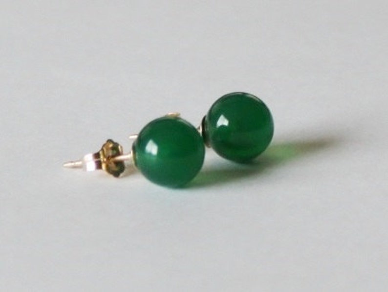 May include: A pair of green gemstone earrings with gold posts.
