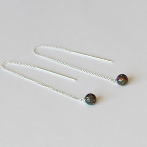 May include: A pair of silver chain earrings with a black and iridescent opal bead at the end of each chain.