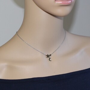 May include: A silver chain necklace with a crescent moon charm and two small star charms.