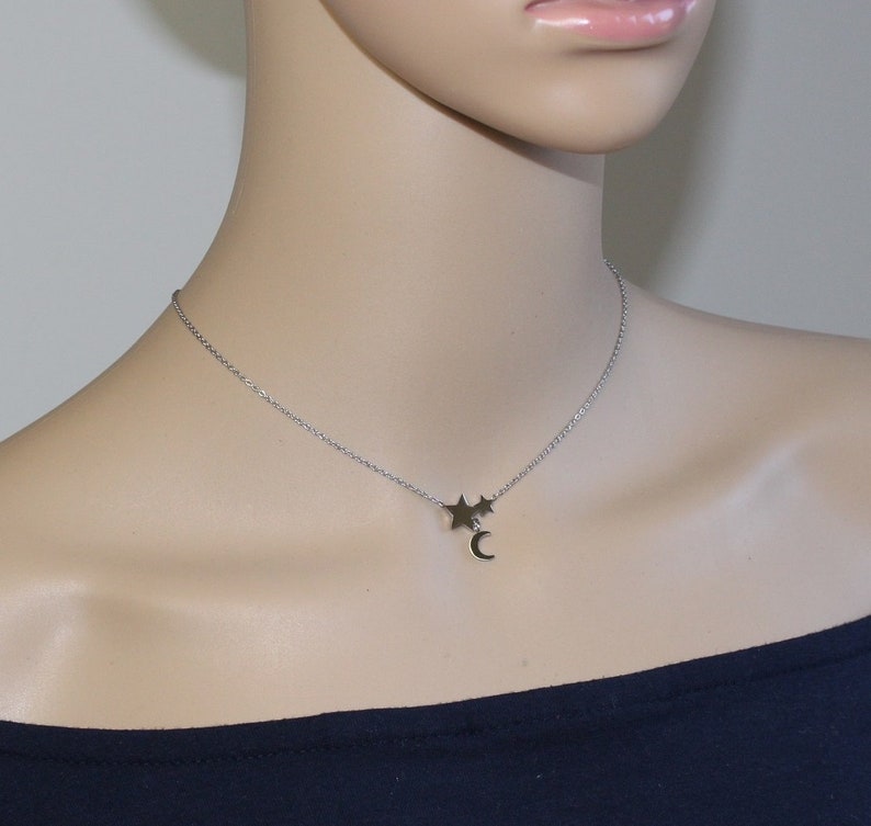 May include: A silver chain necklace with a crescent moon charm and two small star charms.