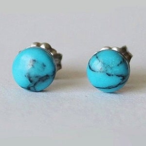 May include: A pair of silver stud earrings with turquoise stones. The stones are a light blue color with dark blue veins.