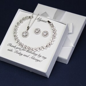 Puede incluir: Una caja de regalo blanca con un conjunto de collar, pulsera y pendientes de plata. La caja tiene el texto "Gracias por estar a mi lado. Hoy y siempre!" y el nombre "Alyssa" escrito en ella.