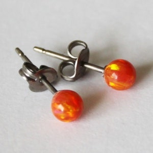 May include: A pair of silver stud earrings with orange and yellow opal stones.