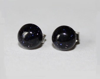 May include: A pair of silver stud earrings with round blue gemstone accents. The gemstones have a speckled appearance.