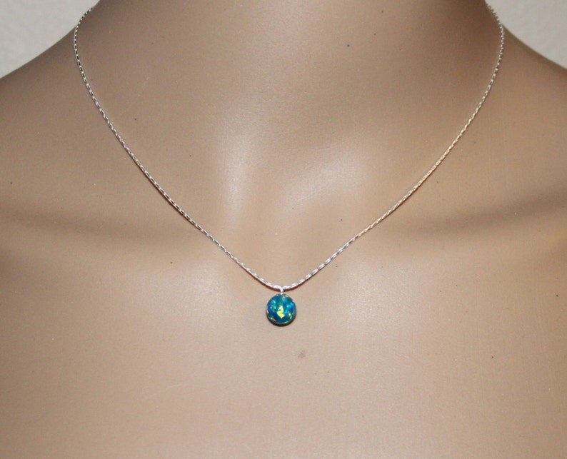 May include: A silver chain necklace with a small, round, blue and green opal pendant.