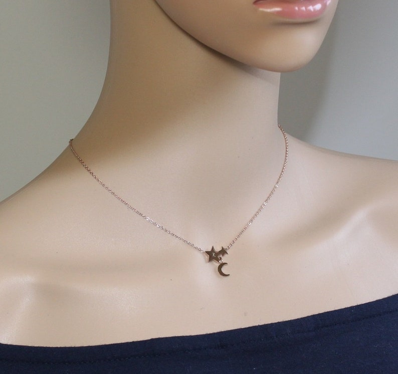 May include: A delicate gold necklace with a crescent moon charm and two small star charms.