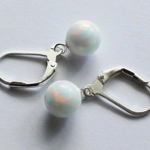 May include: A pair of silver earrings with white opal round stones. The earrings have lever back closures.