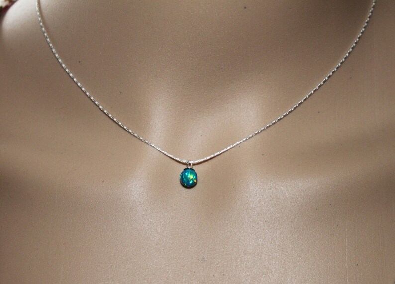 May include: A silver chain necklace with a small, teardrop-shaped blue opal pendant.