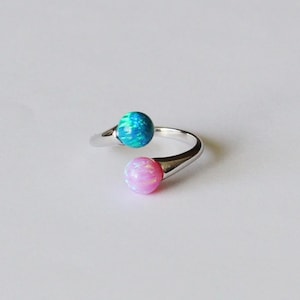 May include: A silver ring with two round opals, one blue and one pink.