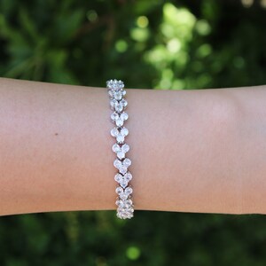Puede incluir: Un brazalete de plata con una doble fila de piedras de circonita c&uacute;bica transparentes engastadas en forma de coraz&oacute;n.