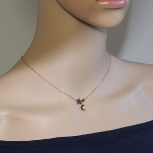 May include: A delicate gold necklace with a crescent moon charm and two small star charms.