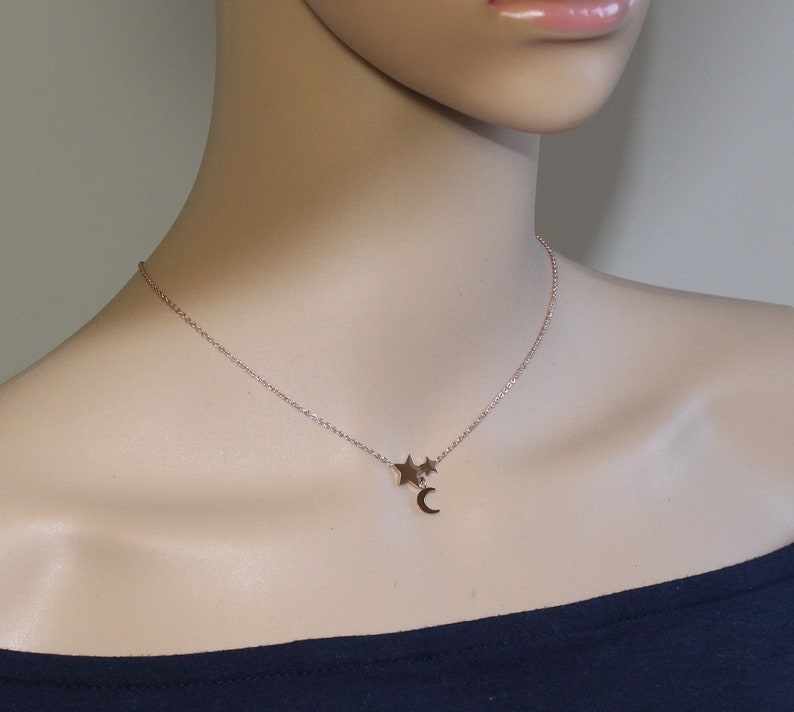 May include: A delicate gold necklace with a crescent moon charm and two small star charms.