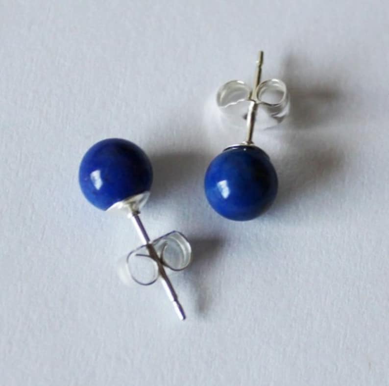 May include: A pair of silver stud earrings with round blue lapis lazuli stones.