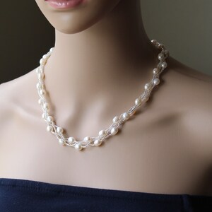 Op de afbeelding: Een witte parelketting met meerdere strengen parels. De ketting is gemaakt van kleine, ronde parels en is een klassiek en elegant sieraad.