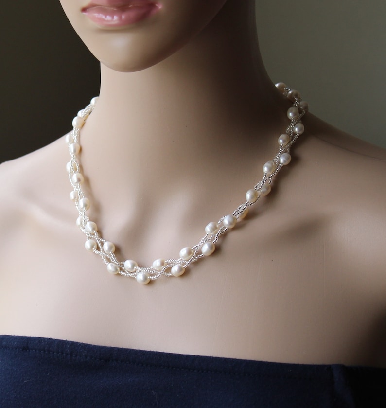 Op de afbeelding: Een witte parelketting met meerdere strengen parels. De ketting is gemaakt van kleine, ronde parels en is een klassiek en elegant sieraad.