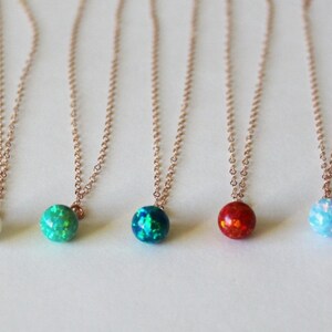 May include: Five delicate necklaces with small opal pendants in various colors, including white, green, blue, and red. The necklaces are made of rose gold chain.