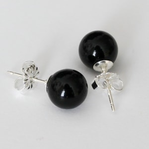 May include: A pair of black onyx stud earrings with silver posts and butterfly backs.