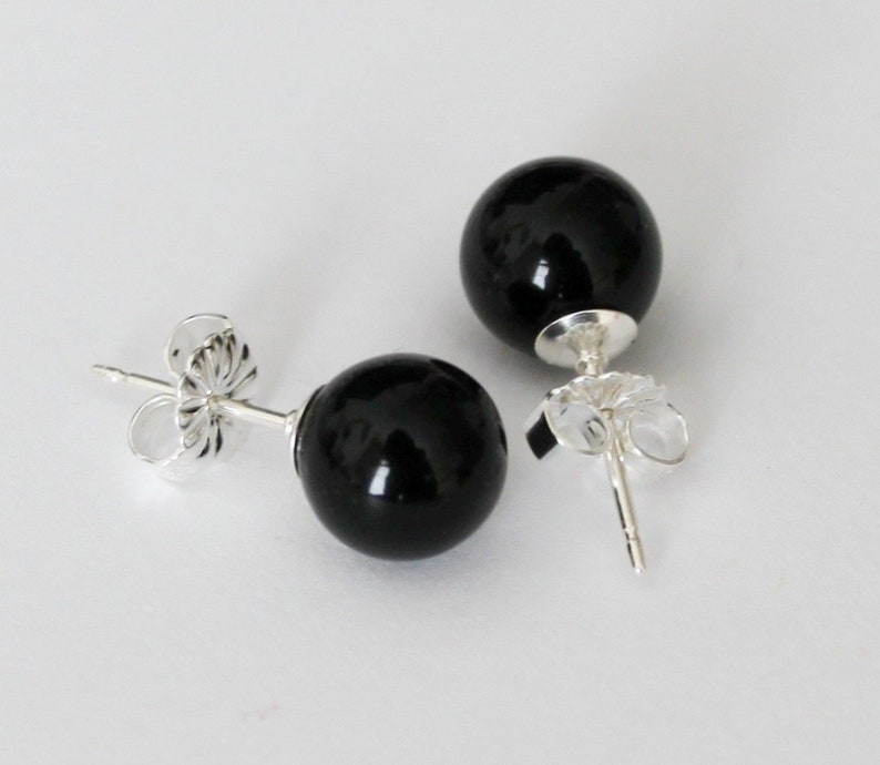 May include: A pair of black onyx stud earrings with silver posts and butterfly backs.